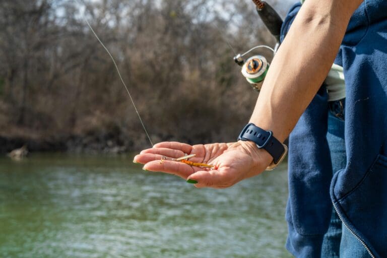 hand holding bait beside river